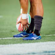 Stock image of a person holding a rugby ball. Photo: Unsplash/Hanson Lu