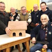 Finishing a covered bird feeding tray are Biggar Shed members, left to right: Lindsay Moffat, treasurer Ian Veale, MP David Mundell, Richard Crosse, chair Ranald McGregor and fund-raising co-ordinator Phil Cave. Photo: Bryan Armstrong
