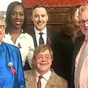 HIV campaigner and music superstar Sir Elton John, seated, with husband David Furnish, back, third from left, and parliamentarians, left to right: committee co-chairs Baroness Liz Barker, Florence Eshalomi MP and David Mundell MP