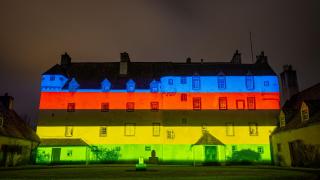 Traquair House lit with the UCI Cycling World Championships rainbow - blue, red, black, yellow, and green - to celebrate six months until event